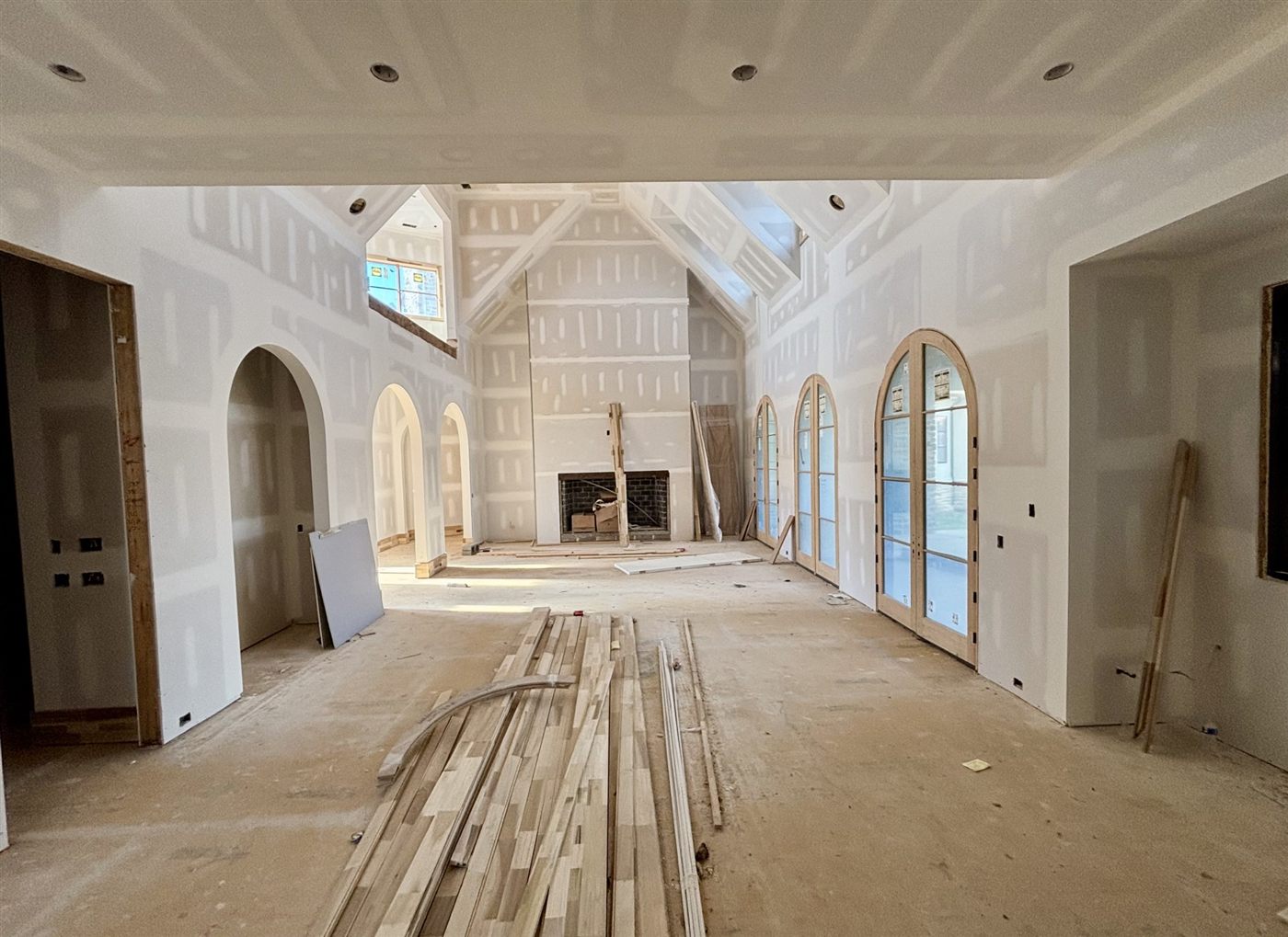 Double height great room during construction with arched openings